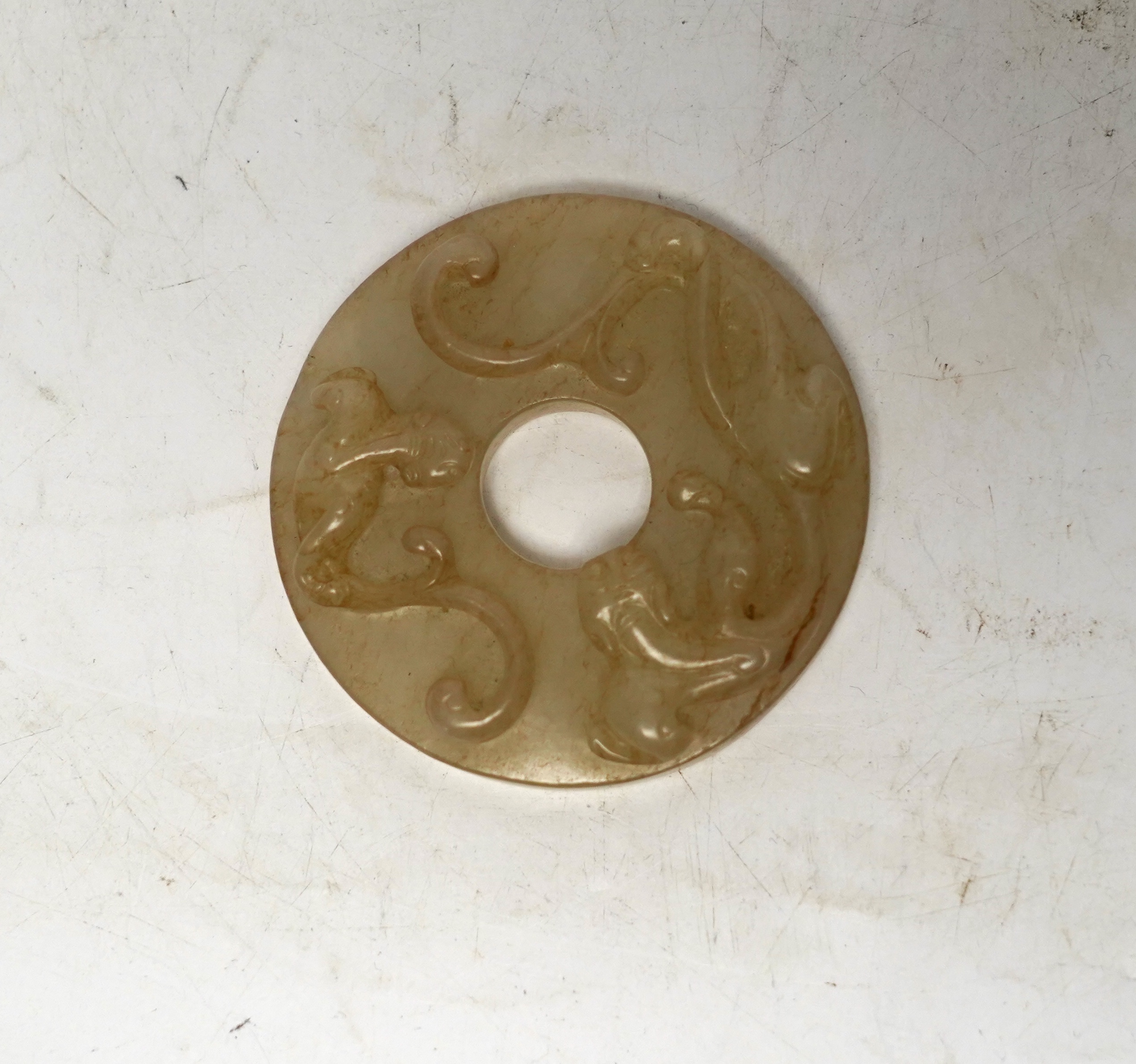 An 18th century Chinese mottled jade bi disc, decorated with two carved chilong, 5.8cm diameter